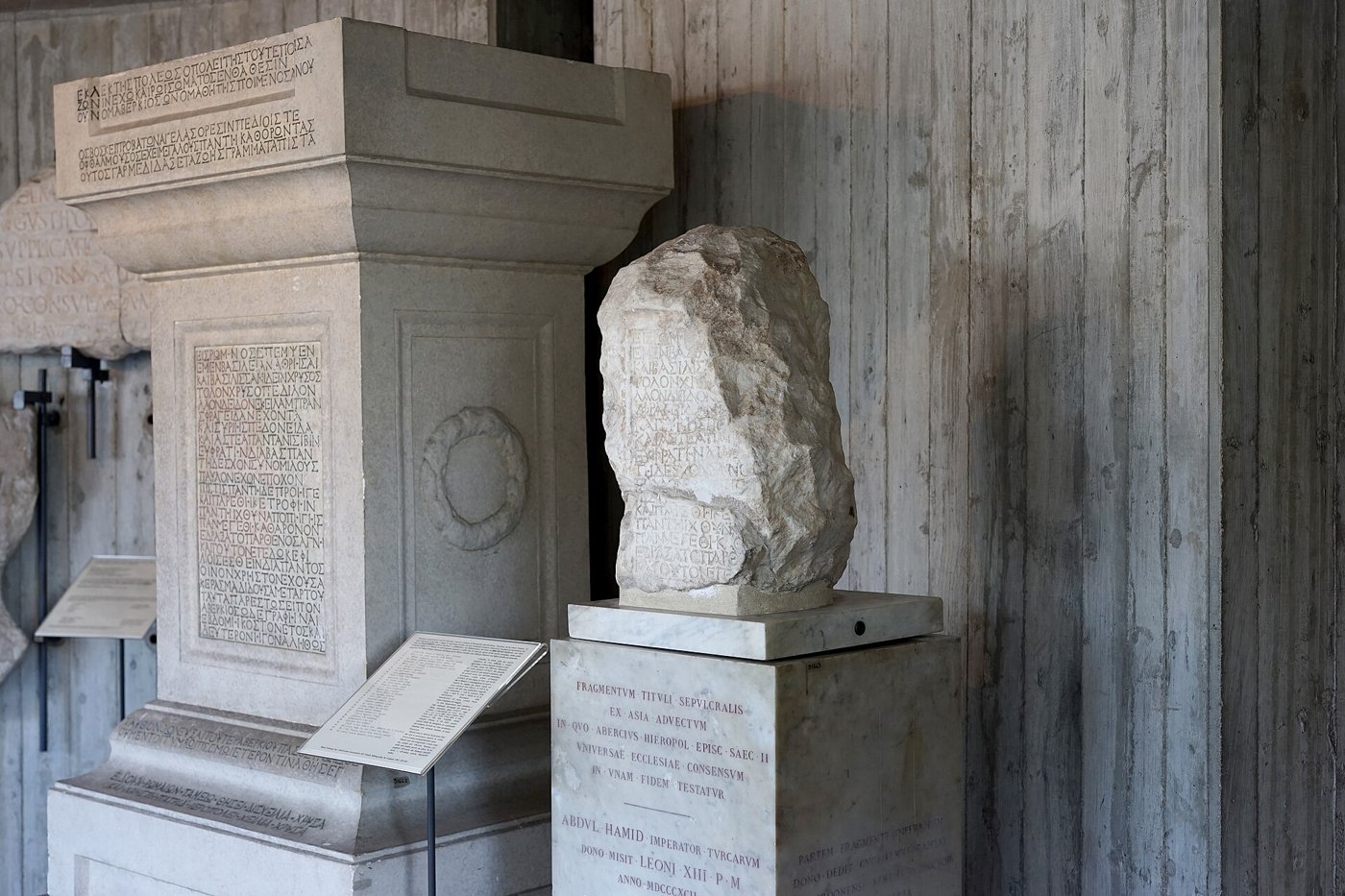 The surviving marble fragment of the Abercius inscription on its pedestal, beside a modern full-size reconstruction of the original stone