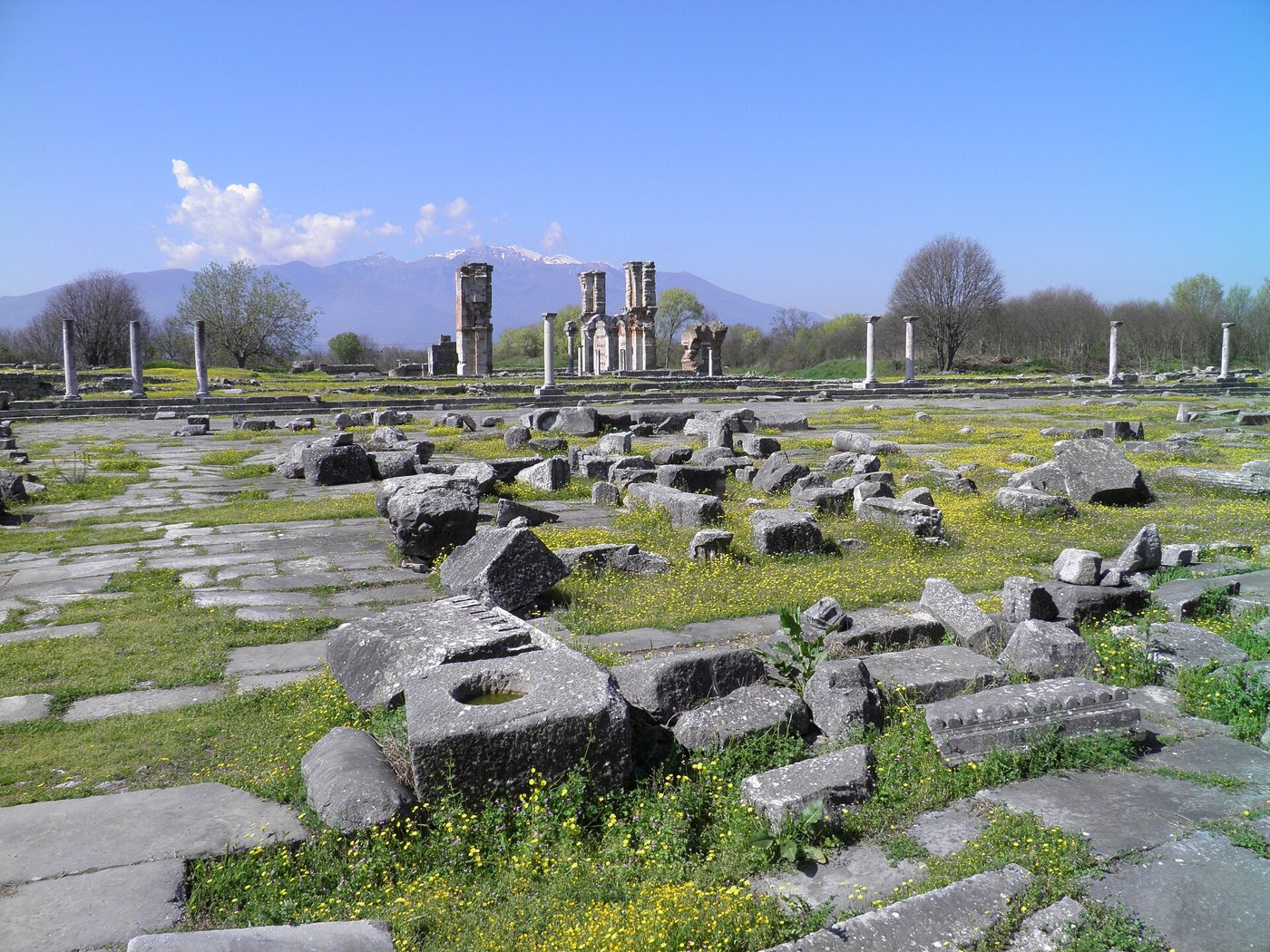 Paving and scattered blocks of the Roman forum at Philippi, with the standing piers of the early Christian Basilica B behind